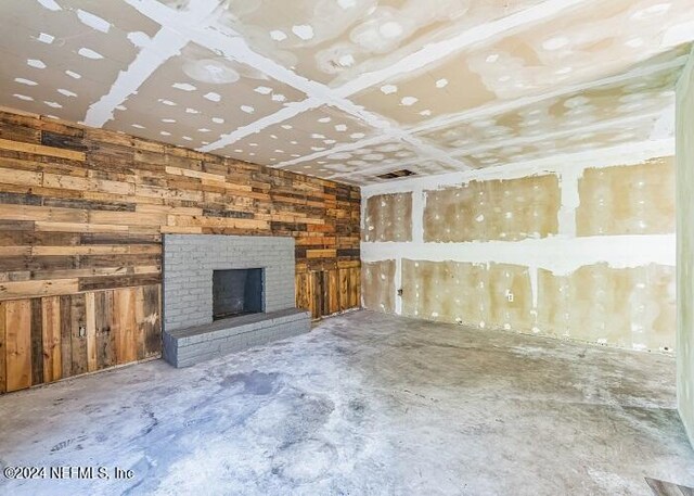 unfurnished living room featuring a brick fireplace and concrete flooring