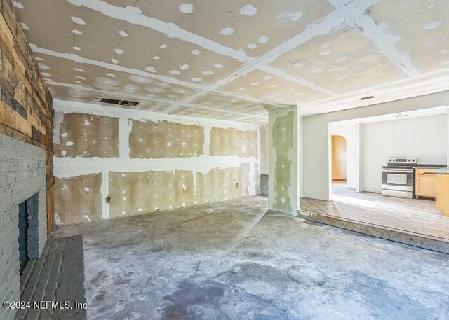 unfurnished living room with a brick fireplace and concrete floors