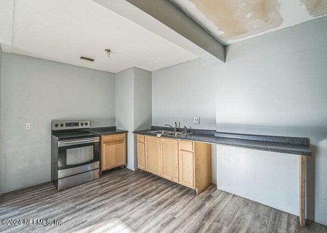 kitchen with beam ceiling, light hardwood / wood-style floors, stainless steel electric range oven, and sink