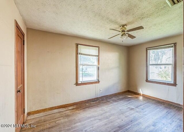 spare room featuring a wealth of natural light, wood-type flooring, ceiling fan, and a textured ceiling