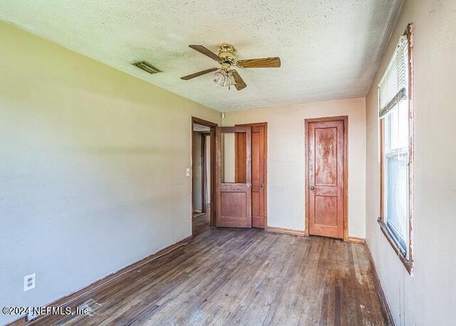 unfurnished bedroom with a textured ceiling, dark hardwood / wood-style flooring, and ceiling fan