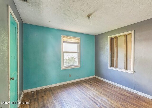 unfurnished room featuring a textured ceiling and hardwood / wood-style flooring