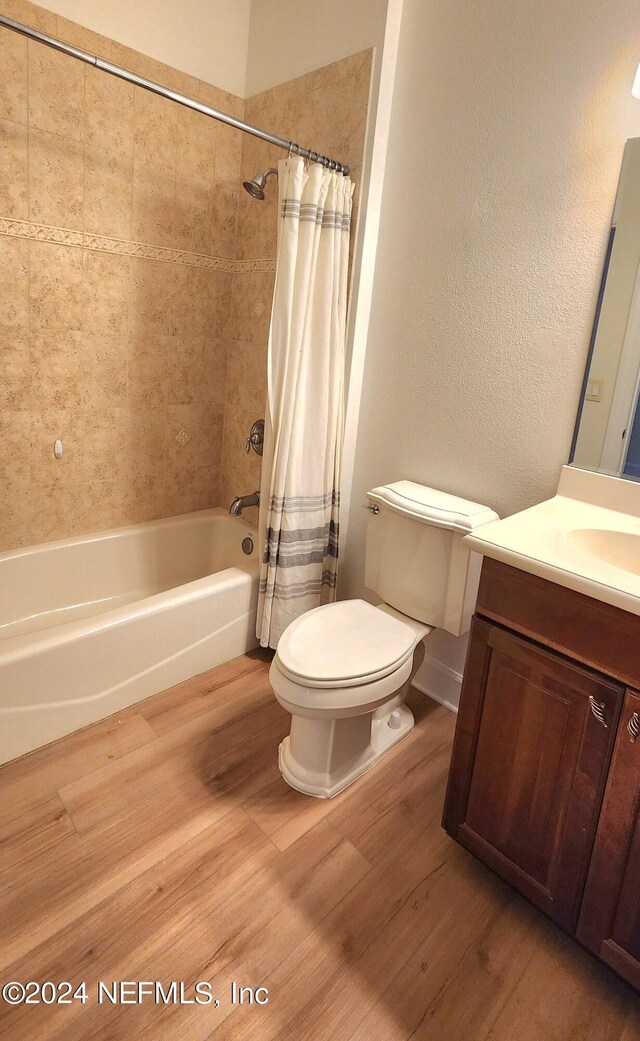 full bathroom featuring wood-type flooring, vanity, toilet, and shower / bathtub combination with curtain