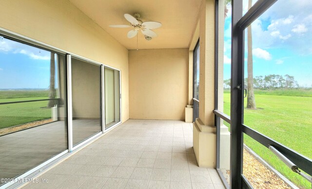 unfurnished sunroom featuring ceiling fan