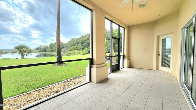 unfurnished sunroom with ceiling fan and a water view