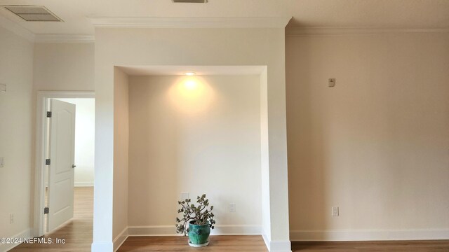 hallway with ornamental molding and wood-type flooring