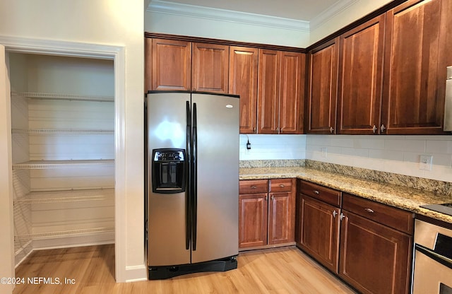 kitchen featuring appliances with stainless steel finishes, light wood-type flooring, light stone counters, and tasteful backsplash