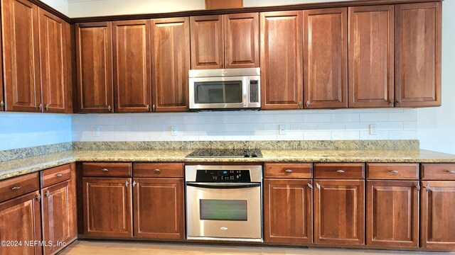 kitchen featuring appliances with stainless steel finishes, light stone counters, and tasteful backsplash