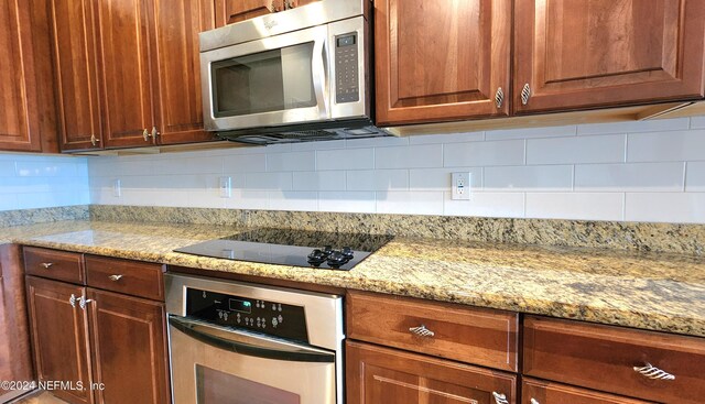 kitchen with light stone countertops, stainless steel appliances, and tasteful backsplash