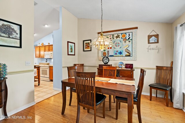 dining area featuring an inviting chandelier, light wood-type flooring, and vaulted ceiling