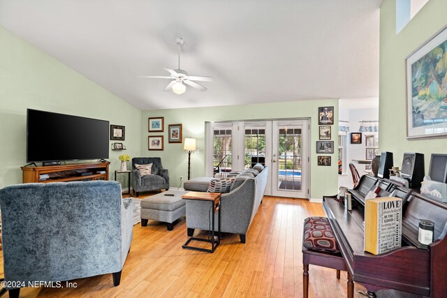 living room with light wood-type flooring, vaulted ceiling, ceiling fan, and french doors