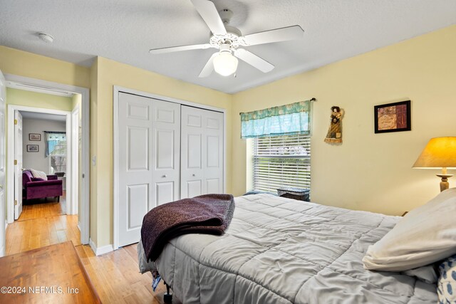 bedroom with light hardwood / wood-style floors, a closet, ceiling fan, and a textured ceiling