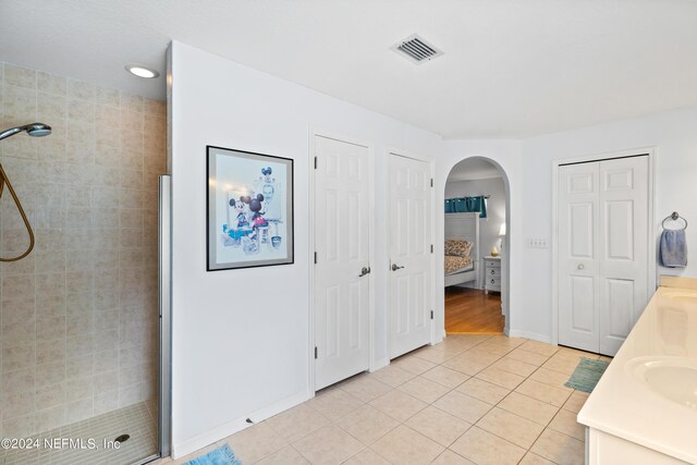 bathroom featuring vanity, tile patterned flooring, and a tile shower