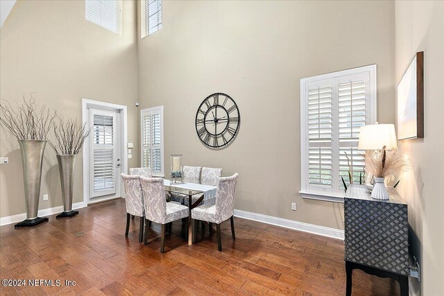 dining space featuring a high ceiling, dark hardwood / wood-style flooring, and plenty of natural light