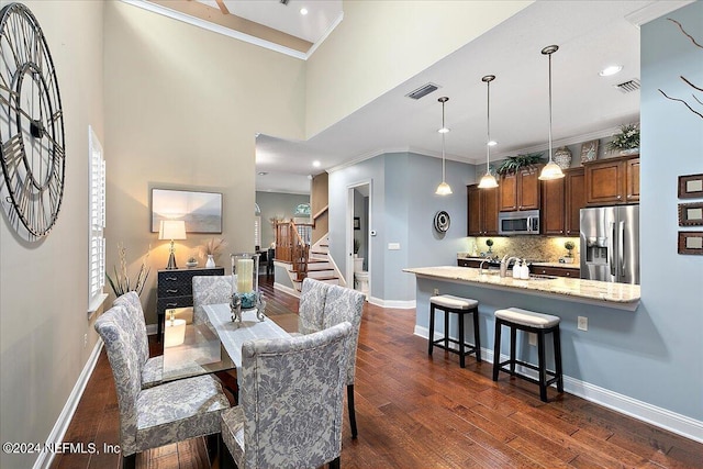 dining space featuring ornamental molding, sink, and dark wood-type flooring