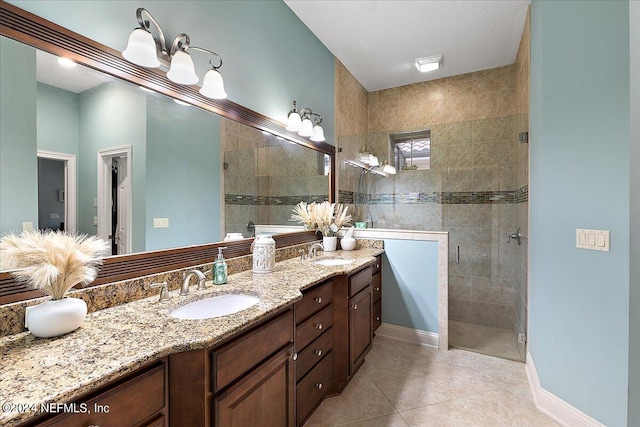 bathroom featuring tiled shower, vanity, and tile patterned flooring