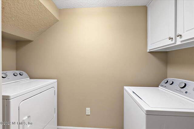 laundry room featuring cabinets, a textured ceiling, and washer and dryer