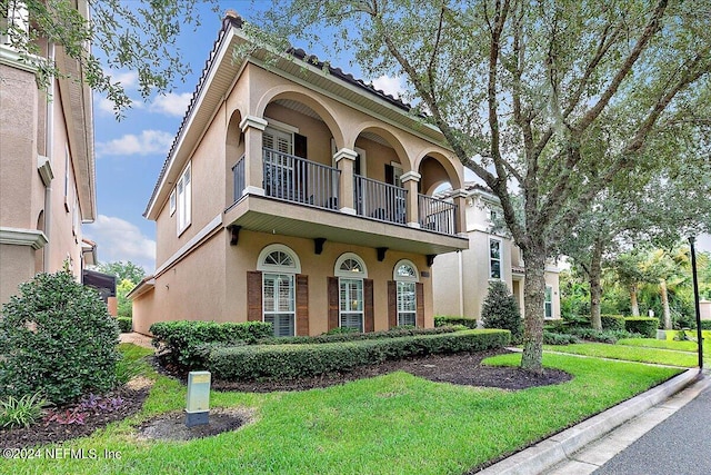 mediterranean / spanish-style house featuring a balcony and a front yard