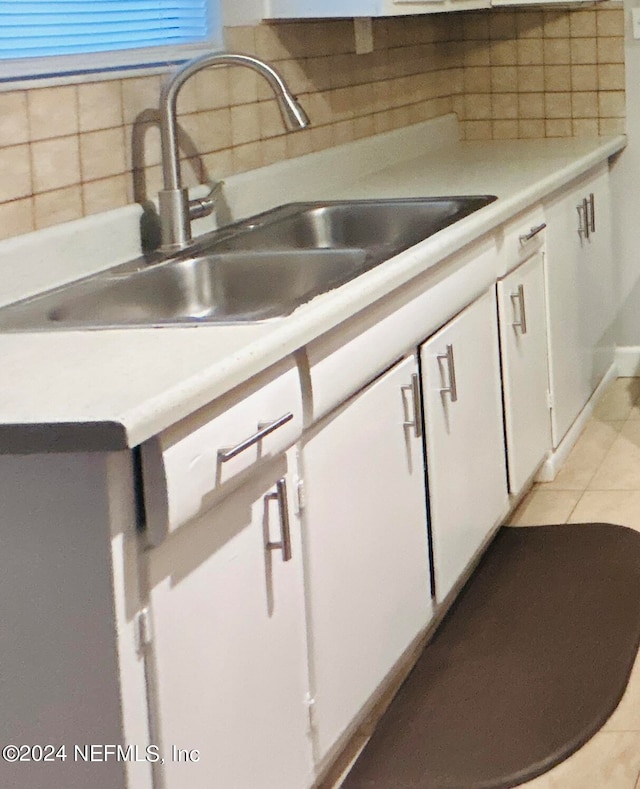 kitchen with light tile patterned floors, sink, decorative backsplash, and white cabinetry