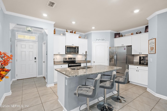 kitchen with a center island with sink, appliances with stainless steel finishes, ornamental molding, and decorative backsplash