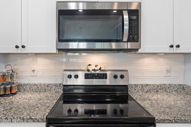 room details with appliances with stainless steel finishes, white cabinetry, and light stone countertops