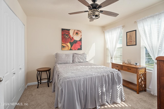 bedroom featuring ceiling fan, light colored carpet, and a closet