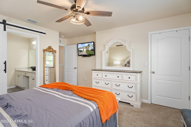 carpeted bedroom featuring ensuite bath, ceiling fan, sink, and a barn door