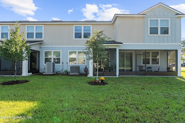 rear view of property with cooling unit and a lawn