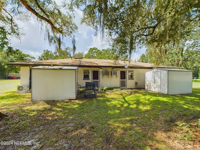 back of property featuring a storage unit, an outbuilding, a yard, and ac unit
