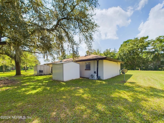 back of house with a lawn, an outdoor structure, a shed, and ac unit