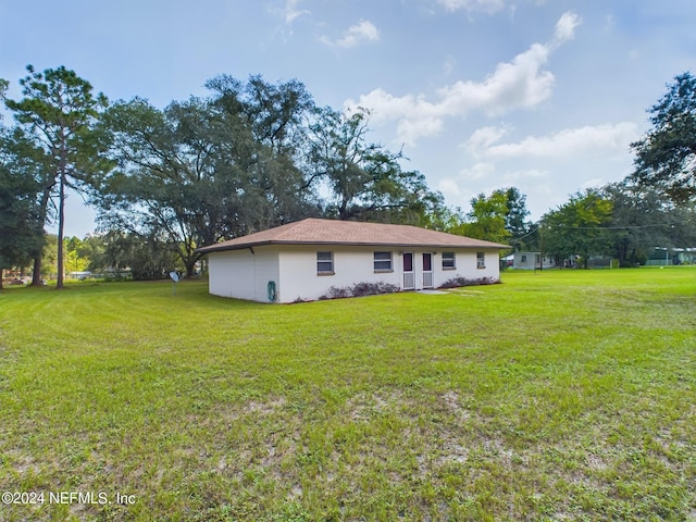 rear view of property with stucco siding and a lawn