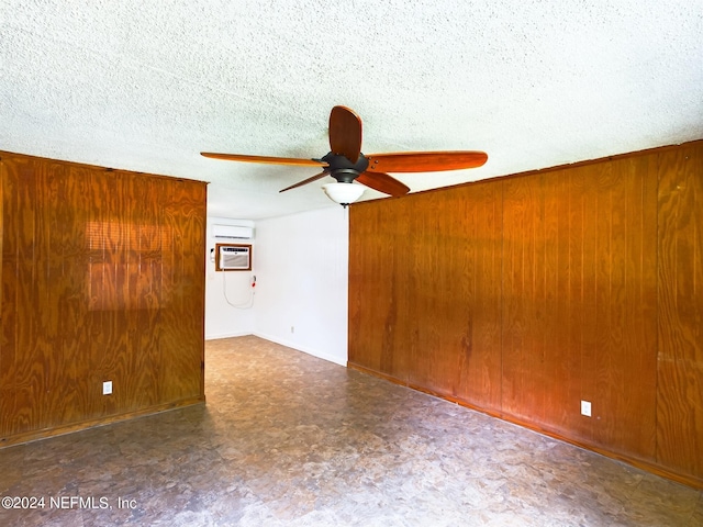 unfurnished room featuring a textured ceiling, wooden walls, ceiling fan, and a wall mounted air conditioner