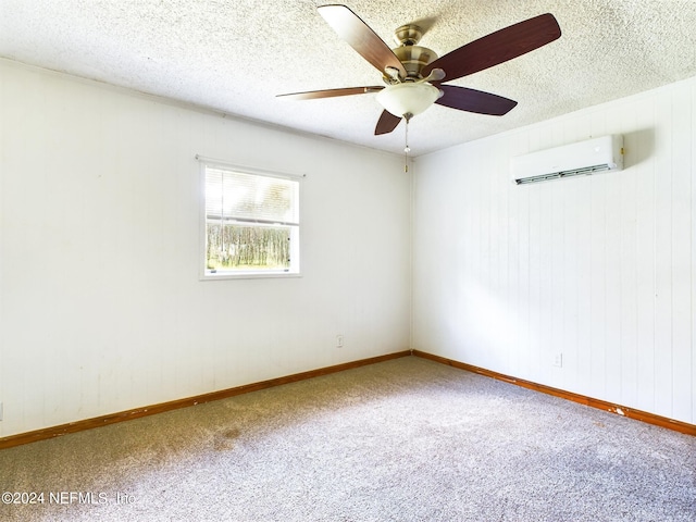 carpeted spare room with a textured ceiling, wood walls, ceiling fan, baseboards, and an AC wall unit