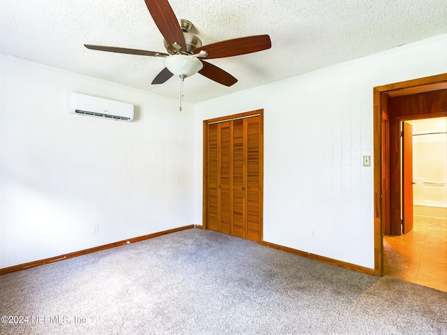 unfurnished bedroom featuring a closet, a wall unit AC, carpet floors, and a textured ceiling