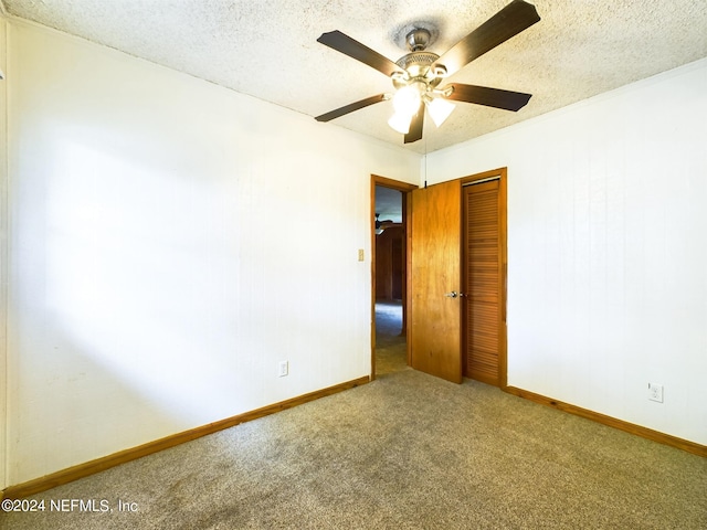 empty room featuring a textured ceiling, ceiling fan, carpet, and baseboards