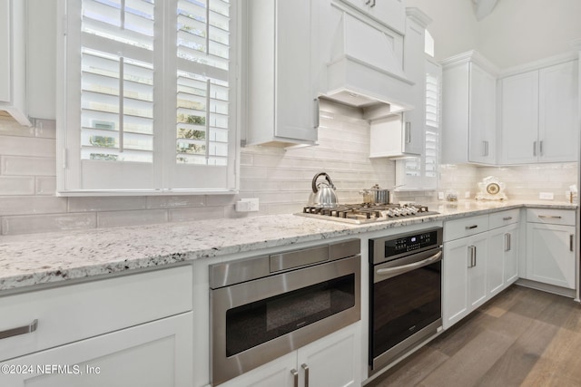 1505 Lakeside Ct, Fernandina Beach, FL 32034 - kitchen with white cabinetry, premium range hood, appliances with stainless steel finishes, and backsplash