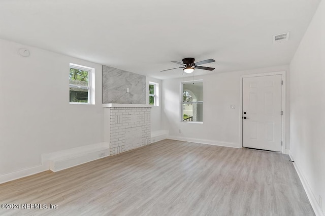 unfurnished living room with ceiling fan, a fireplace, and light hardwood / wood-style floors