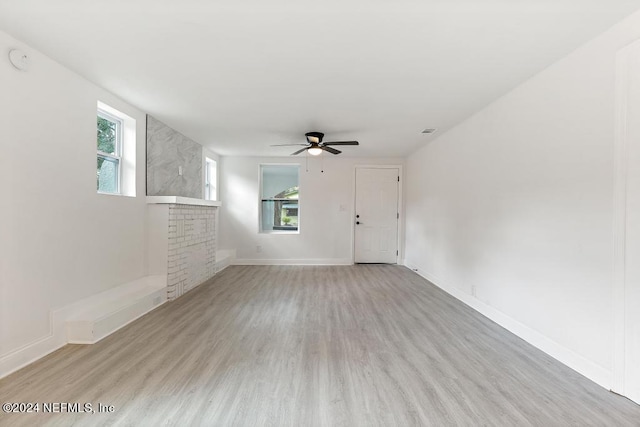 unfurnished living room featuring light wood-type flooring, a fireplace, and ceiling fan