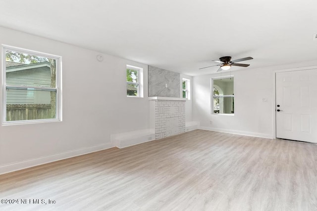 unfurnished living room with light hardwood / wood-style floors, a large fireplace, and ceiling fan