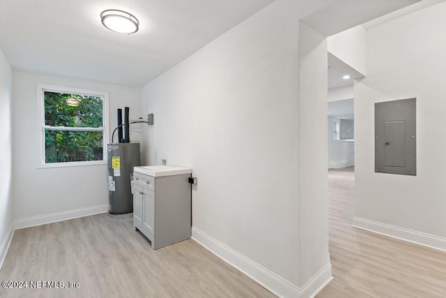 clothes washing area with electric water heater, electric panel, and light hardwood / wood-style flooring