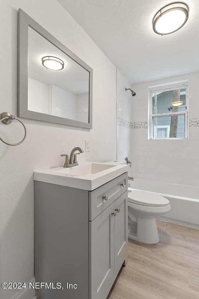 full bathroom with vanity, a textured ceiling, toilet, hardwood / wood-style floors, and tiled shower / bath