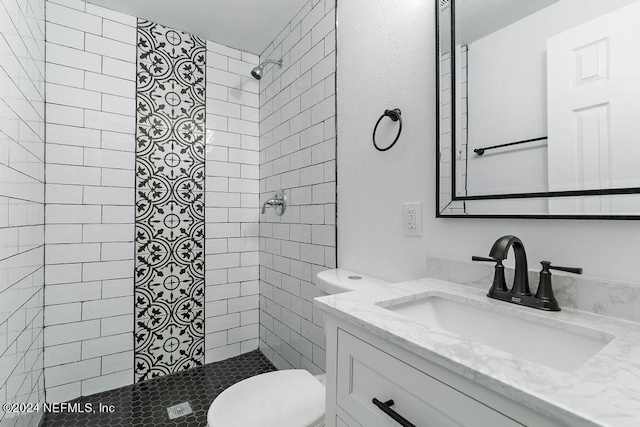 bathroom featuring tiled shower, vanity, and toilet