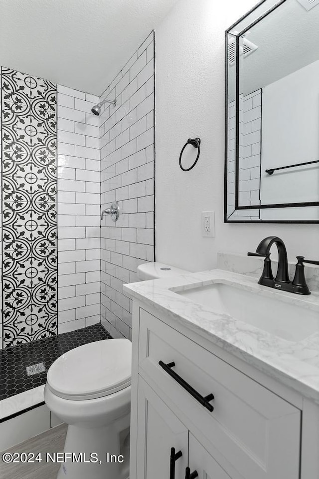 bathroom featuring tiled shower, vanity, and toilet