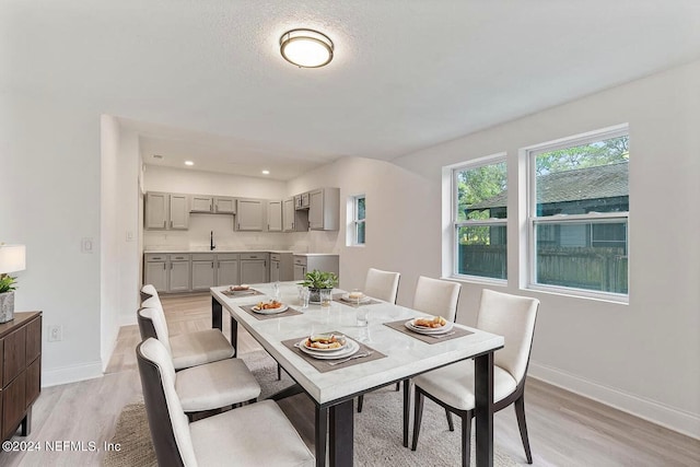 dining area with light wood-type flooring, a textured ceiling, and sink