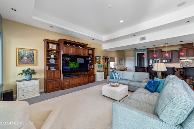 carpeted living room featuring a tray ceiling