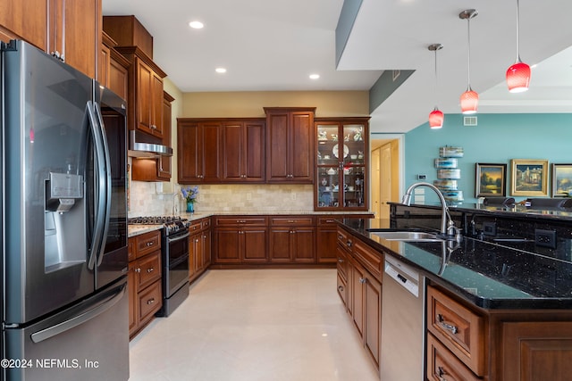 kitchen with appliances with stainless steel finishes, sink, backsplash, dark stone counters, and pendant lighting