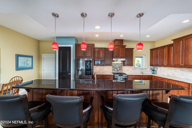 kitchen with a large island, appliances with stainless steel finishes, a kitchen bar, and hanging light fixtures