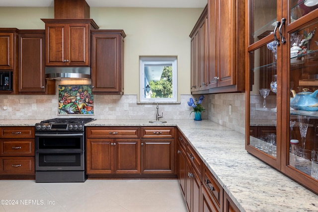 kitchen featuring sink, backsplash, stainless steel range with gas cooktop, light stone counters, and ventilation hood