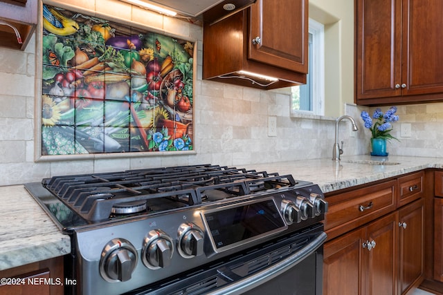 kitchen featuring black range with gas cooktop, tasteful backsplash, sink, and light stone counters