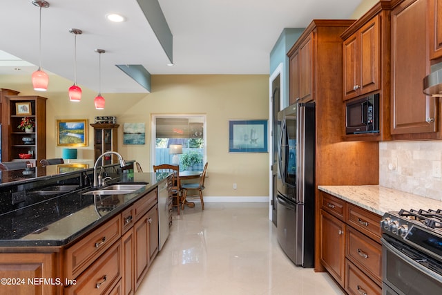 kitchen featuring tasteful backsplash, appliances with stainless steel finishes, dark stone counters, sink, and decorative light fixtures